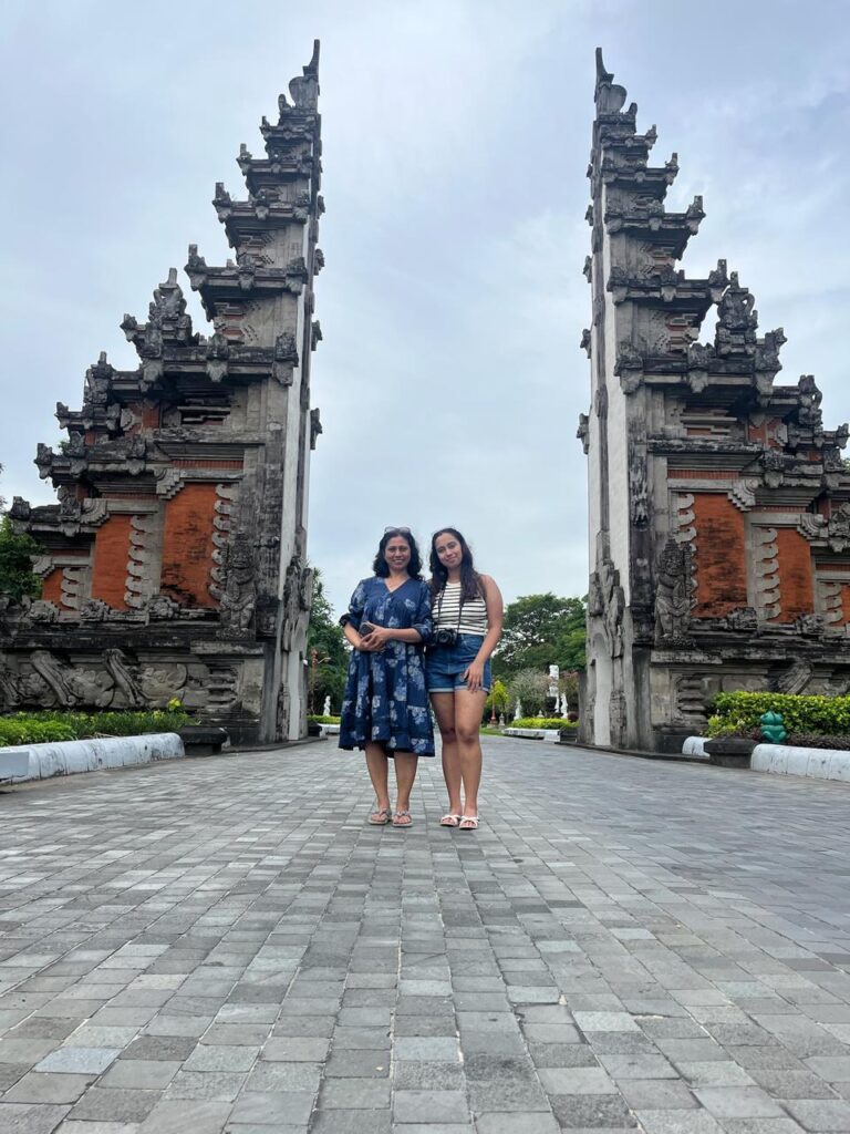 Mother and daughter posing in front of traditional Balinese candi bentar gate