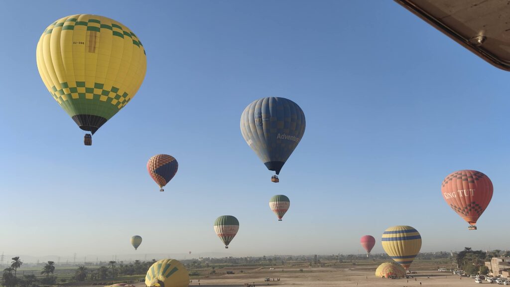 Colorful hot air balloons flying over Luxor’s ancient temples and the Nile River valley during sunrise in Egypt