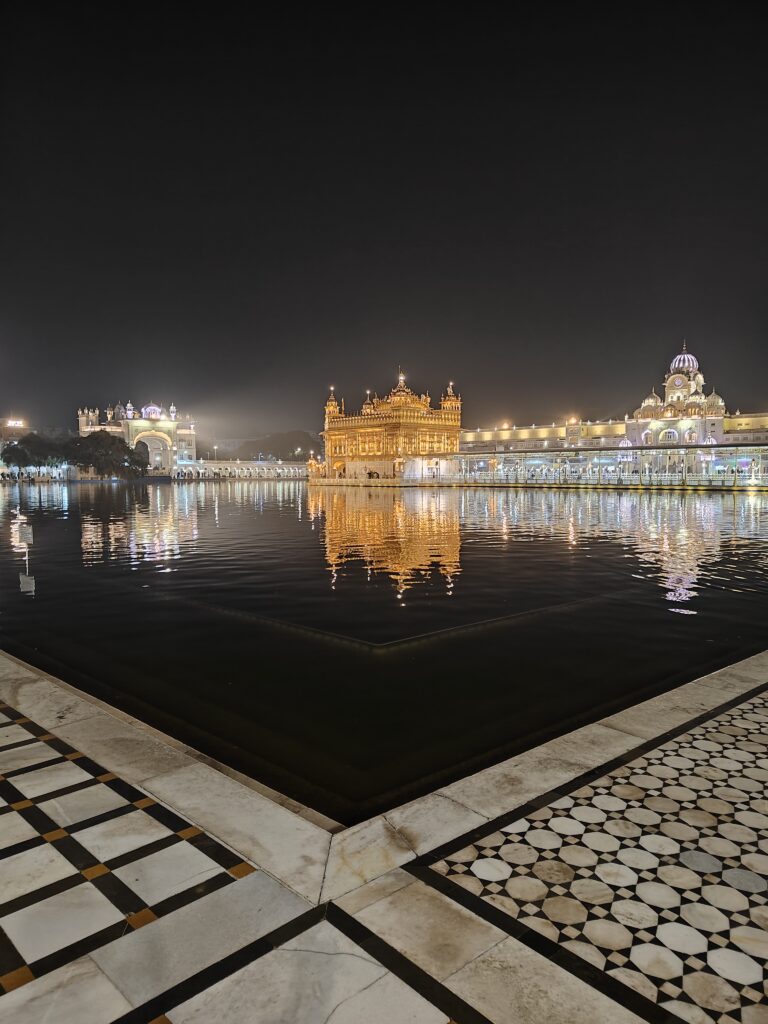 Golden Temple illuminated at night with reflection in the holy water tank, surrounded by lit pathways in Amritsar.