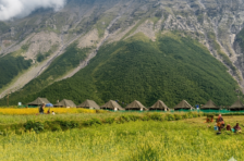 Swiss tents in green fields at Sural Bhatori village in Pangi Valley surrounded by steep Himalayan mountains (Himalayan Overland Safari)