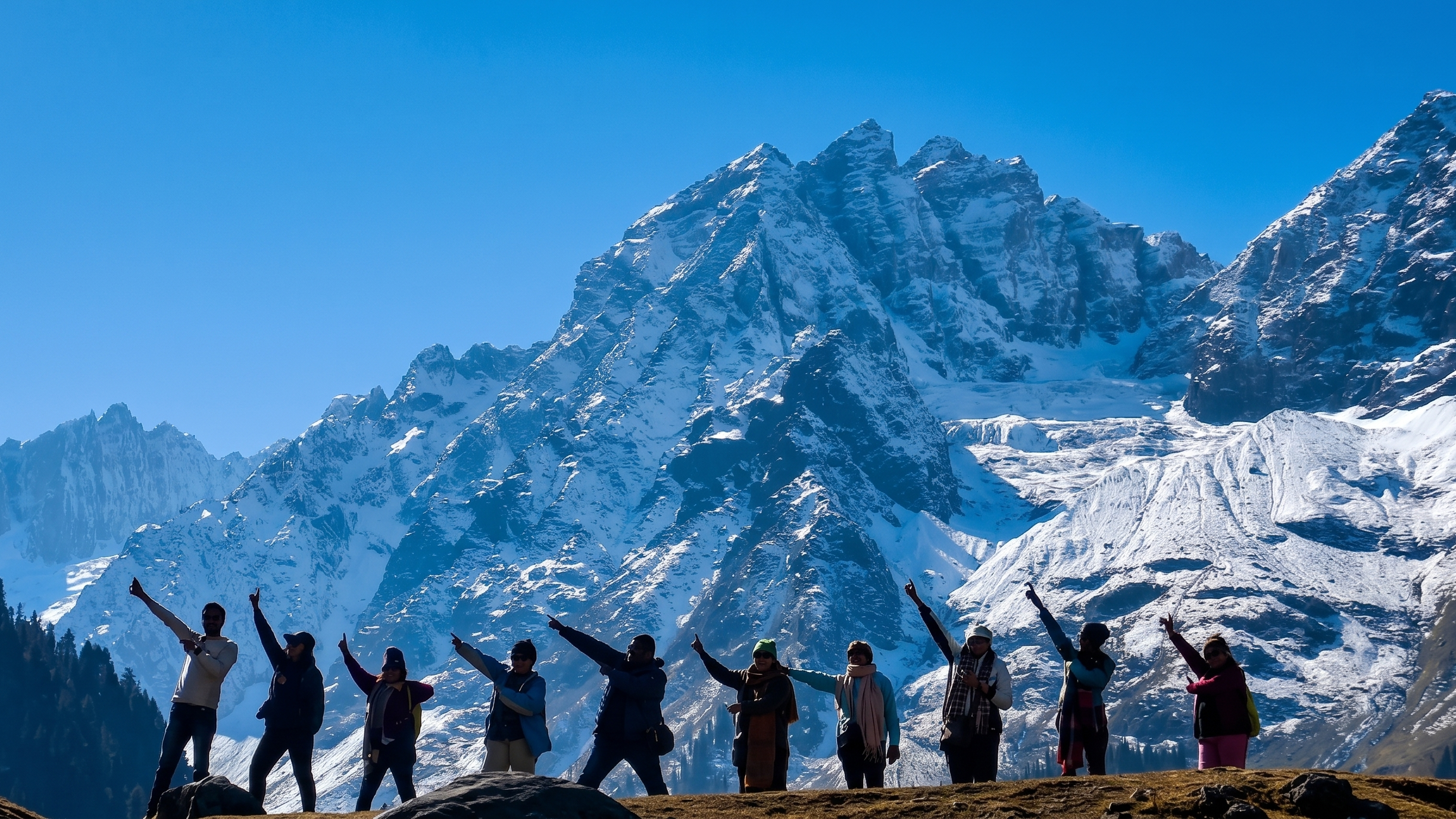 A group of nine travelers stand in a row on a ridge, silhouetted against the colossal, ice-carved slopes of Thajiwas Glacier under a bright blue sky.