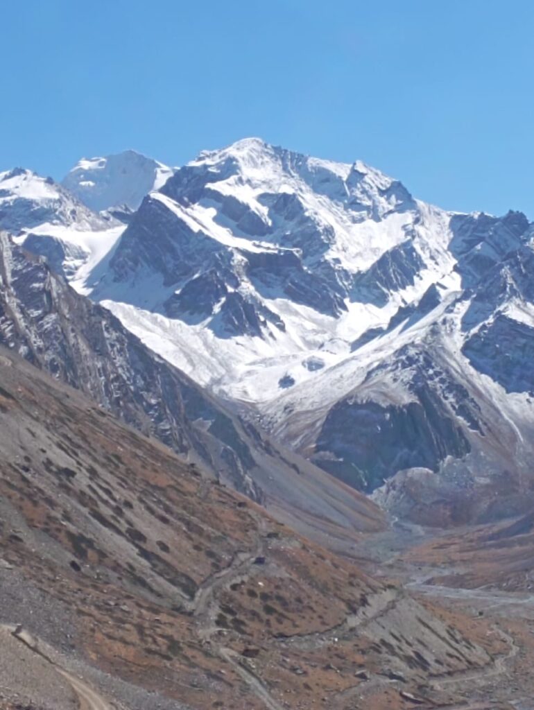 A majestic mountain peak where snow patterns clearly form the sacred Hindu symbol 'OM' against a deep blue sky.