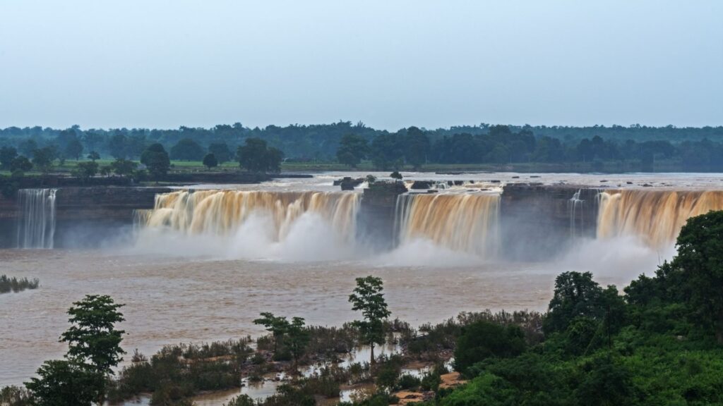 The wide, majestic horseshoe-shaped Chitrakote Waterfall cascading down a rocky cliff under a clear sky in Bastar, Chhattisgarh.