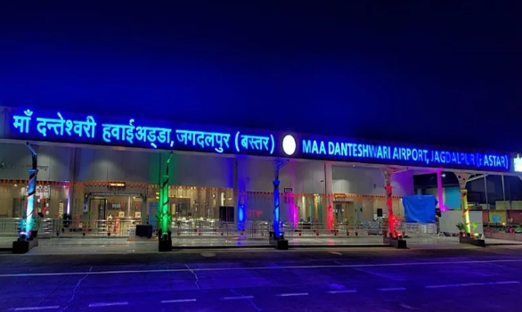The illuminated entrance of Maa Danteshwari Airport in Jagdalpur, Bastar, at night, featuring a large glowing blue signboard in Hindi and English.